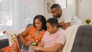 Parent and children looking at a laptop together while holding a credit card, illustrating authorized user vs joint account holder